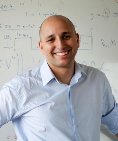 A person smiling in front of a whiteboardDescription automatically generated